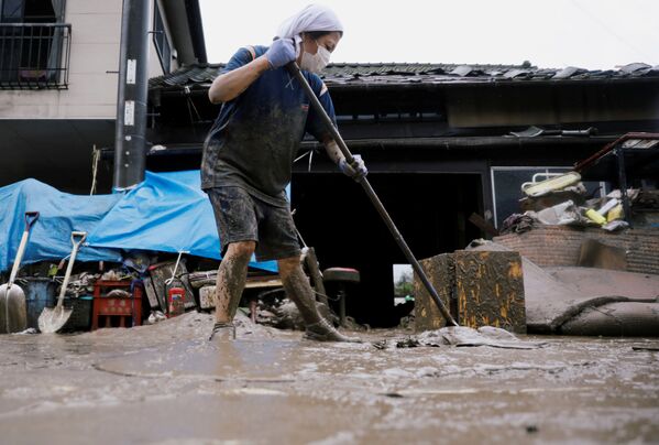 В результате наводнения люди, живущие в горных районах, остались без телефонной связи и водоснабжения. На фото - женщина пытается расчистить территорию у своего дома в городе Хитоёси в префектуре Кумамото, юго-запад Японии - Sputnik Грузия