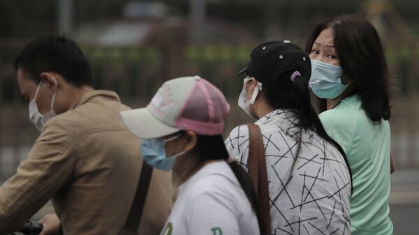 Прохожие в масках идут по улице во время пандемии коронавируса COVID 19 в Пекине Китай - Sputnik Грузия