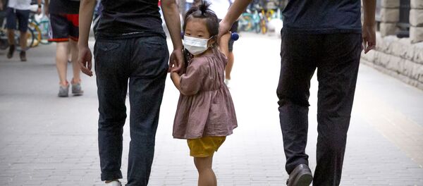 Девочка в медицинской маске идет с родителями по улице во время пандемии коронавируса COVID 19 в Пекине Китай Девочка в медицинской маске идет с родителями по улице во время пандемии коронавируса COVID 19 в Пекине Китай - Sputnik Грузия