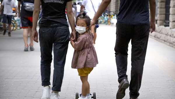 Девочка в медицинской маске идет с родителями по улице во время пандемии коронавируса COVID 19 в Пекине Китай - Sputnik Грузия