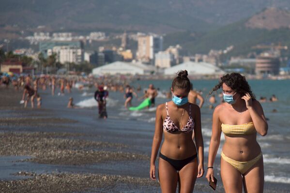 Отрасль туризма в этом году переживает тяжелые времена. На фото изображены девушки в защитных масках на пляже Мизерикордия в Малаге - Sputnik Грузия