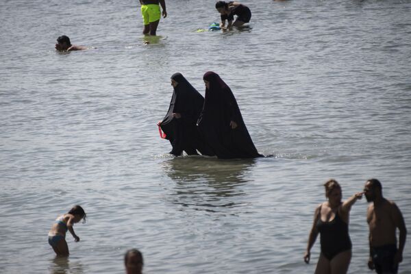 На сегодняшний день туриндустрия предлагает значительные скидки. Мусульманки в чадре купаются в море на пляже в Марселе - Sputnik Грузия
