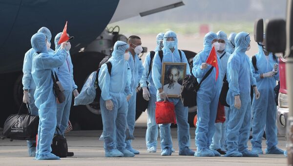 Вьетнамские граждане в защитной одежде во время пандемии COVID 19 с портретом Хо Ши Мина в аэропорту Ханоя - 129 человек, работавших в Экваториальной Гвинее, эвакуировали - Sputnik Грузия