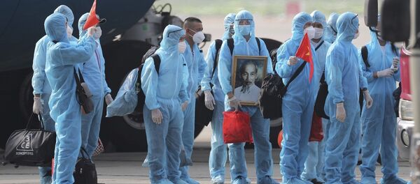 Вьетнамские граждане в защитной одежде во время пандемии COVID 19 с портретом Хо Ши Мина в аэропорту Ханоя - 129 человек, работавших в Экваториальной Гвинее, эвакуировали - Sputnik Грузия