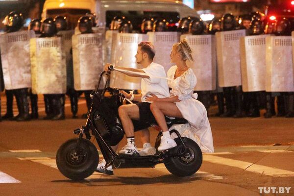 Пара на скутере напротив полицейских во время протестов в Минске  - Sputnik Грузия