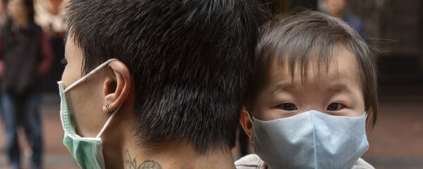 Ребенок в защитной маске на руках отца на одной из улиц в Гонконге - Sputnik Грузия