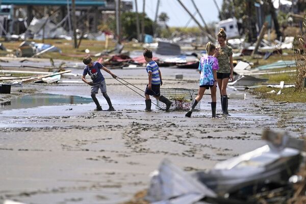 Ураган Лаура ударил и по Гаити. Там погибли более 30 человек, восемь числятся пропавшими без вести.  На фото - подростки на одной из улиц поселка Холли-Бич в Луизиане - Sputnik Грузия