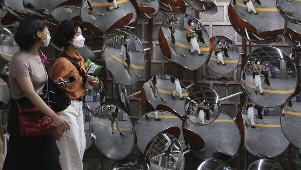 Девушки идут по улице в Сеуле, Южная Корея, в масках и респираторах во время пандемии коронавируса COVID 19 - Sputnik Грузия