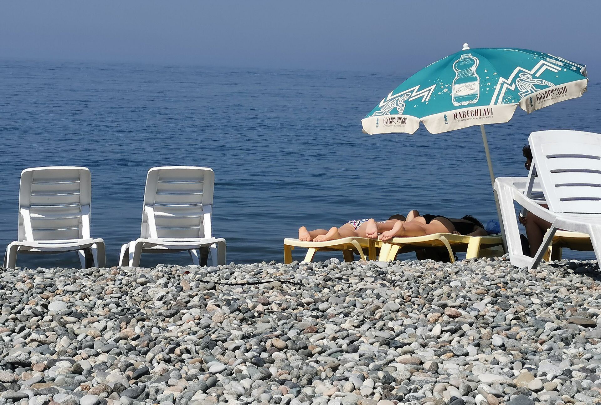 Женщины загорают в солнечный день на берегу моря. Черноморский пляж в Аджарии во время пандемии коронавируса - Sputnik საქართველო, 1920, 20.06.2022