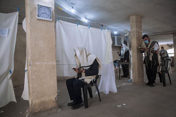 В Израиле введены жесткие ограничения на три недели из-за пандемии коронавируса и резкого увеличения числа заболевших. На фото - ортодоксальные евреи в масках и с соблюдением дистанции возносят утреннюю молитву в своих домах, так как посетить синагоги они не могут - Sputnik Грузия