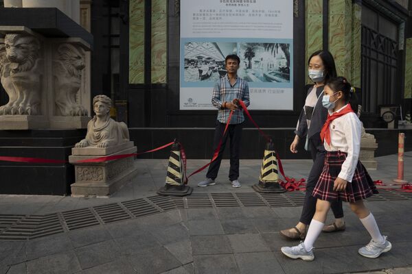 В Китае, в основном, все придерживаются правил ношения масок и дистанцирования. Это и позволило остановить активное распространение коронавируса. Мама с дочкой в масках идут в школу в Пекине мимо одного из оздоровительных клубов - Sputnik Грузия