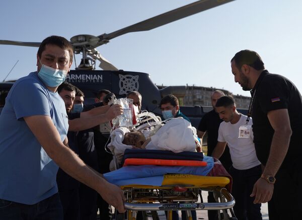 А на этом фото раненых с линии фронта доставляют в больницы. На фото - раненого на носилках транспортируют в медицинский центр Эребуни в Ереване - Sputnik Грузия