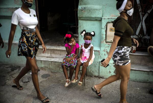 Девочки в масках ждут своих родителей, сидя на стуле в Гаване на Кубе - Sputnik Грузия