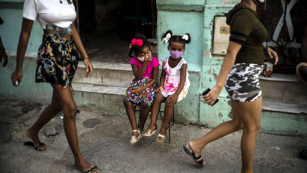 Девочки в масках ждут своих родителей, сидя на стуле в Гаване, Куба - Sputnik Грузия