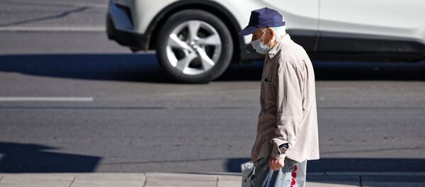 Эпидемия коронавируса. Пожилой мужчина в маске идет по улице - Sputnik Грузия