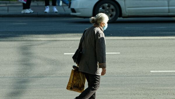 Эпидемия коронавируса. Пожилая женщина в маске идет по улице - Sputnik Грузия