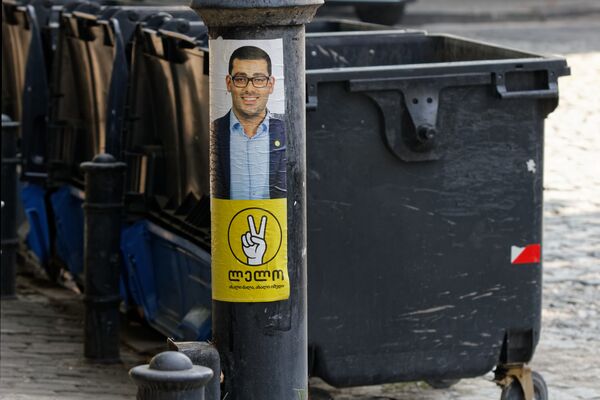 Не самое удачное размещение предвыборной рекламы - плакат оппозиционной партии Лело, наклеенный на столб рядом с мусорными контейнерами - Sputnik Грузия
