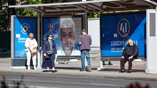 Предвыборная символика и коронавирус. Баннер правящей партии Грузинская мечта на автобусной остановке - Sputnik Грузия