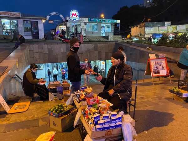 Активисты партий в масках раздают свои буклеты на улицах, а также разносят их по жилым домам, раскладывая у дверей в квартиры. На фото - один из активистов раздает буклеты женщинам, торгующим у метро Сараджишвили в Тбилиси - Sputnik Грузия