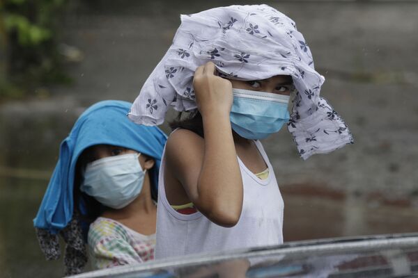 Девочки в медицинских масках пытаются укрыться от дождя на Филиппинах  - Sputnik Грузия