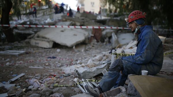 Спасатель во время отдыха на месте разрушенного здания после землетрясения в Измире  - Sputnik Грузия