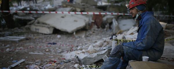 Спасатель во время отдыха на месте разрушенного здания после землетрясения в Измире  - Sputnik Грузия