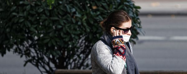 Девушка на улице в маске говорит по телефону - Sputnik Грузия
