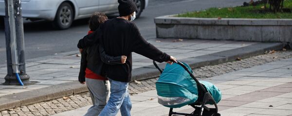 Молодые родители в масках с детской коляской - Sputnik Грузия