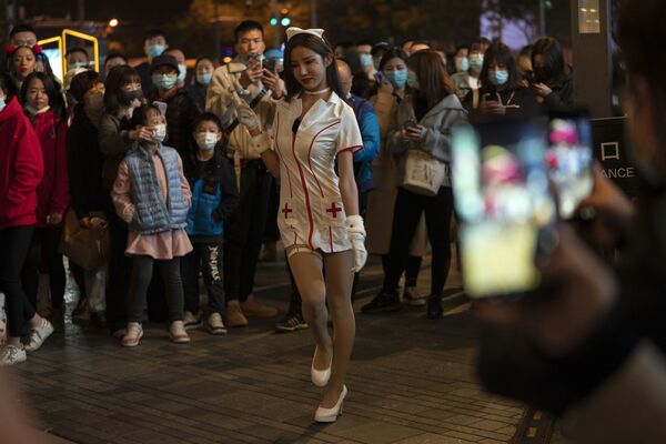 Девушка в костюме медсестры выступает перед толпой в ночь Хэллоуина в торговом районе Пекина - Sputnik Грузия