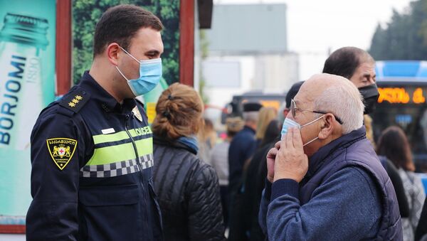 Сотрудники полиции раздают на улице маски прохожим во время эпидемии коронавируса  - Sputnik Грузия