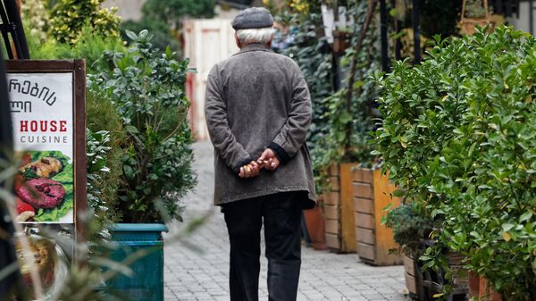 Пенсионер идет по улице мимо закрытых кафе и ресторанов - Sputnik Грузия