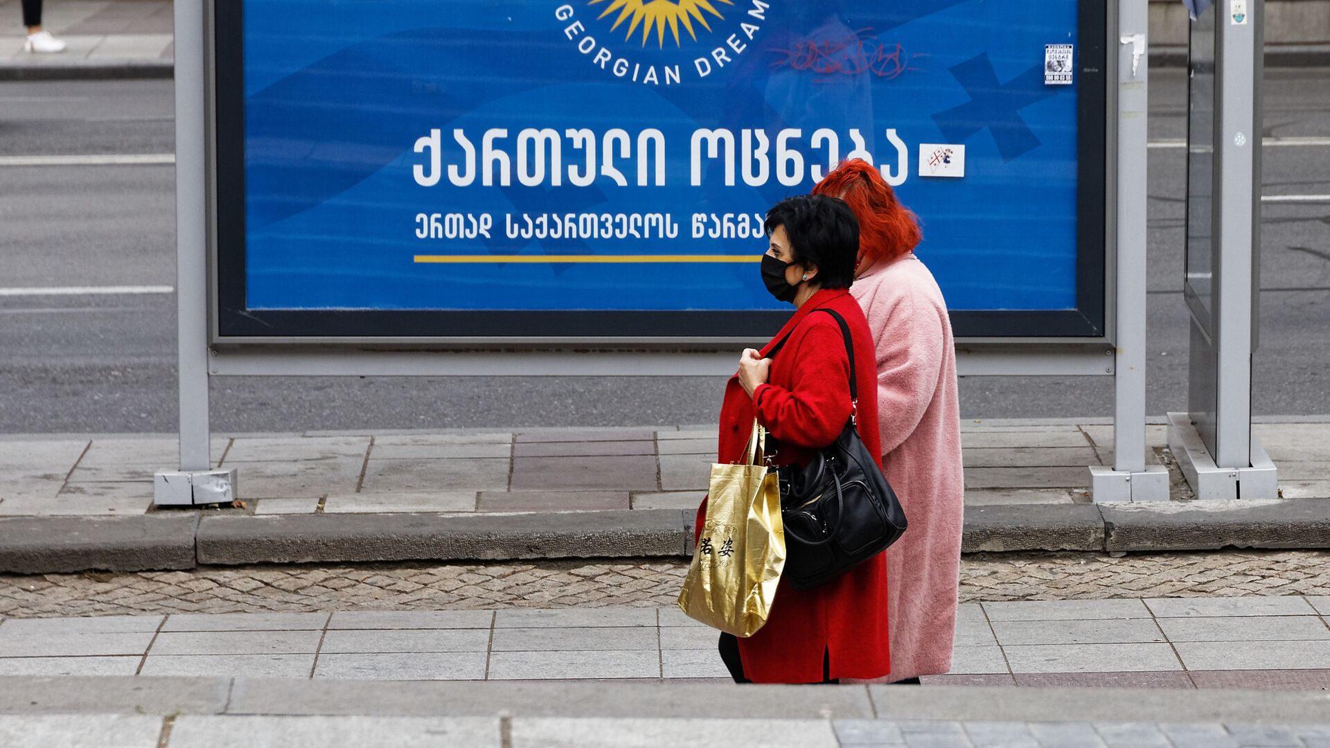 Баннер партии Грузинская мечта - мимо остановки идут женщины в масках защищаясь от коронавируса - Sputnik Грузия, 1920, 19.09.2021