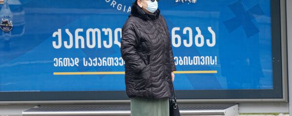 Второй тур выборов - предвыборный баннер партии Грузинская мечта. Женщина на остановке в маске Второй тур выборов - предвыборный баннер партии Грузинская мечта. Женщина на остановке в маске - Sputnik Грузия