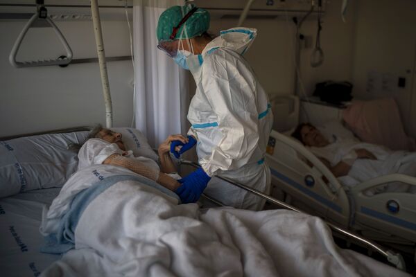 Медсестра Марта Фернандес держит за руку одну из своих пациенток, 94-летнюю Марию Терезу Аргуллос, в одной из больниц Барселоны, Испания. Худшее в этой пандемии - это то, как пациенты справляются с ней в одиночку. Труднее всего видеть, как они умирают в одиночестве, - говорит Фернандес - Sputnik Грузия