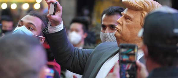 Люди на Таймс-сквер в Нью-Йорке фотографируют человека в маске Дональда Трампа - Sputnik Грузия