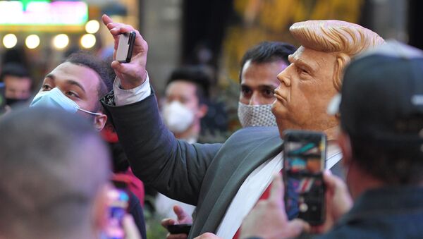 Люди на Таймс-сквер в Нью-Йорке фотографируют человека в маске Дональда Трампа - Sputnik Грузия