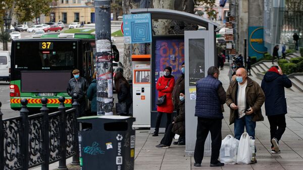 Черная пятница - покупатели на автобусной остановке с покупками в масках - Sputnik Грузия
