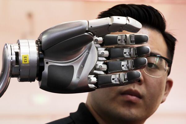 Посетитель разглядывает роботизированную руку, приводимую в движение перчаткой Kinfinity Glove, в Международном выставочном центре в Пекине - Sputnik Грузия