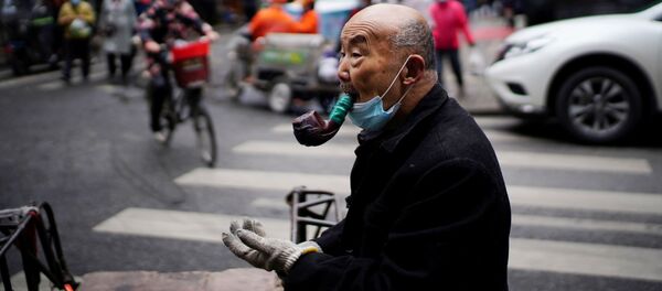 Пожилой мужчина курит трубку на уличном рынке в Ухане - Sputnik Грузия