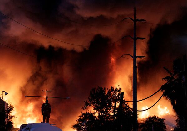 Пожарный стоит на резервуаре с водой во время пожара на заводе по переработке металлолома компании Deacero в Гуадалупе, на окраине Монтеррея в Мексике - Sputnik Грузия
