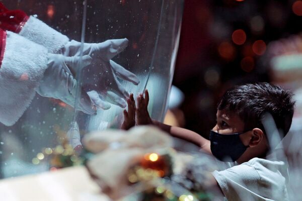 Ребенок общается с Санта Клаусом через пластиковый экран в шоппинг-центре в Бразилии - Sputnik Грузия