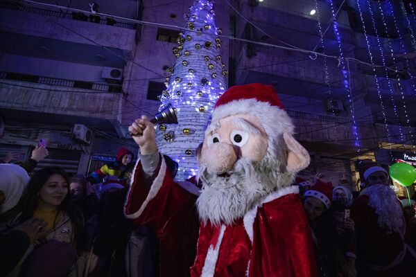 Мужчина в костюме Санта-Клауса во время празднования Рождества в сирийском городе Эль-Камышлы - Sputnik Грузия
