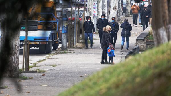 Эпидемия коронавируса - мужчины в капюшонах и масках идут по улице - Sputnik Грузия