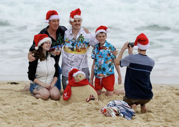 Семья в рождественских колпаках фотографируется на пляже в Сиднее - Sputnik Грузия