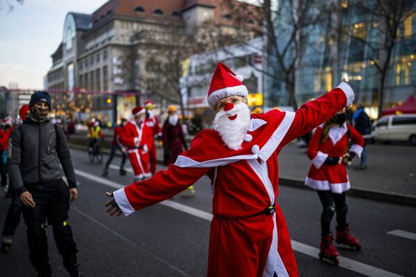 Люди в костюмах Санта-Клауса на роликовых коньках и велосипедах во время шествия в Берлине - Sputnik Грузия