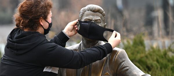 Эпидемия коронавируса - девушка в маске одевает защитную маску на памятник Рональду Рейгану - Sputnik Грузия