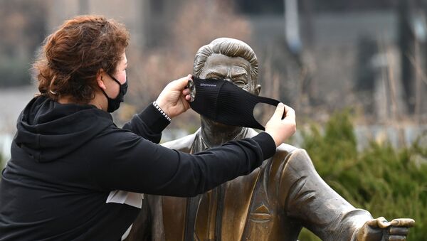 Эпидемия коронавируса - девушка в маске одевает защитную маску на памятник Рональду Рейгану - Sputnik Грузия