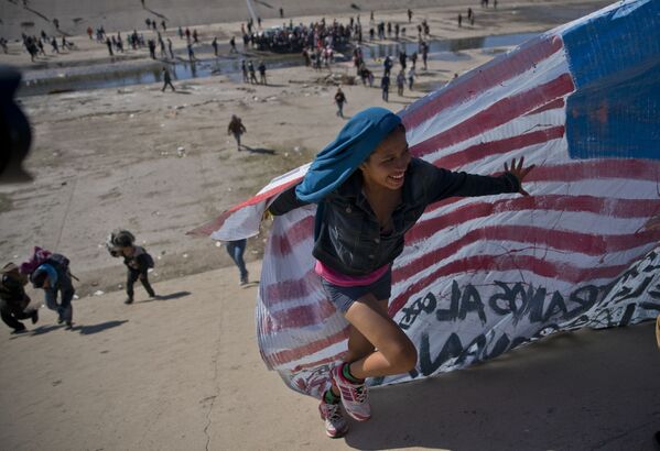 Женщина-мигрантка с флагом на границе США и Мексики - Sputnik Грузия