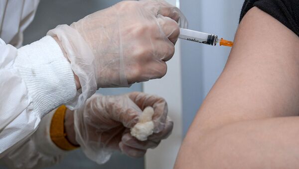 Медицинский сотрудник вводит женщине вакцину от COVID-19 - Sputnik Грузия