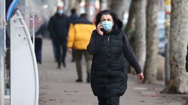 Эпидемия коронавируса и социальная дистанция - женщина в маске идет по улице и говорит по телефону - Sputnik Грузия